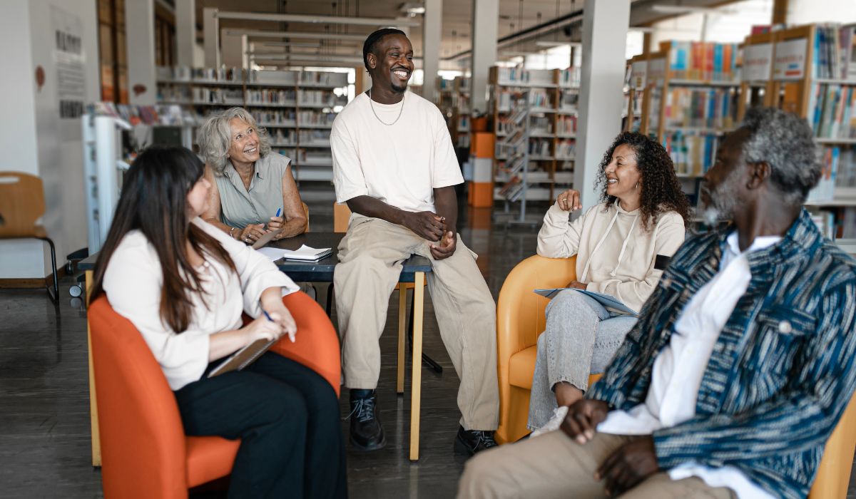 Five people having a conversation in a library.