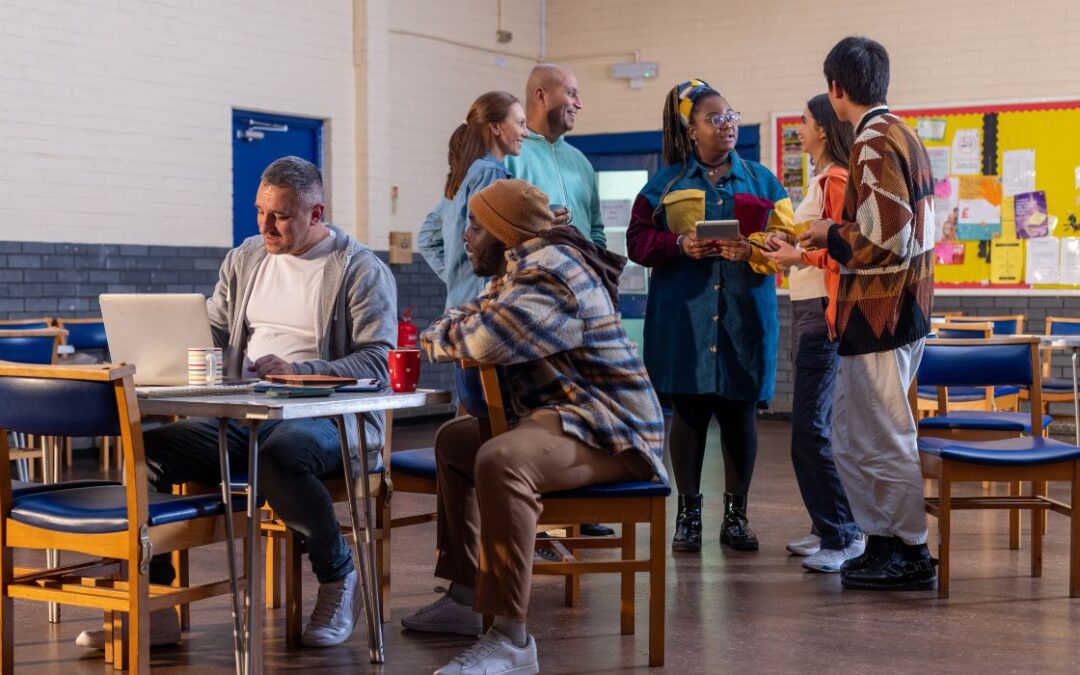 A group of people chatting and drinking tea in a community hall.